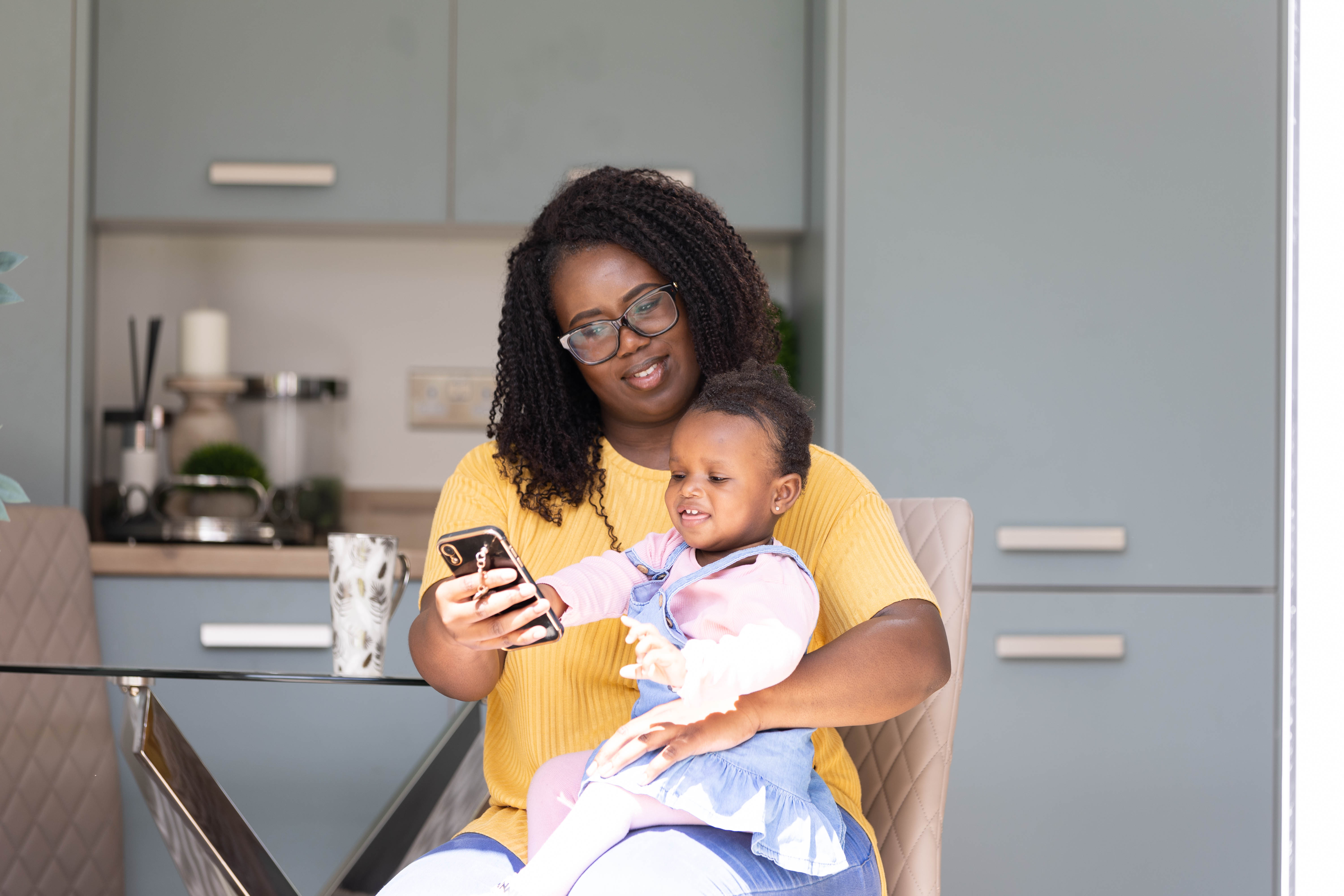 YHG Adult female and child on phone in kitchen Your home hub