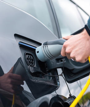 Man Plugging Charger Into Electric Car Charge Station Man Plugging Charger Into Electric Car Charge Station