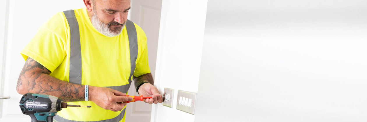 man uses screwdriver to fix light socket